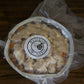 A vacuum sealed foil pan of gluten and dairy free apple crisp on a wooden surface. Made in the kitchen of Nystrom Orchard in Worthington Minnesota.