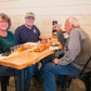 Three people sitting at a table with cold pressed apple cider. Hosted by Nystrom Orchard in Worthington Minnesota.