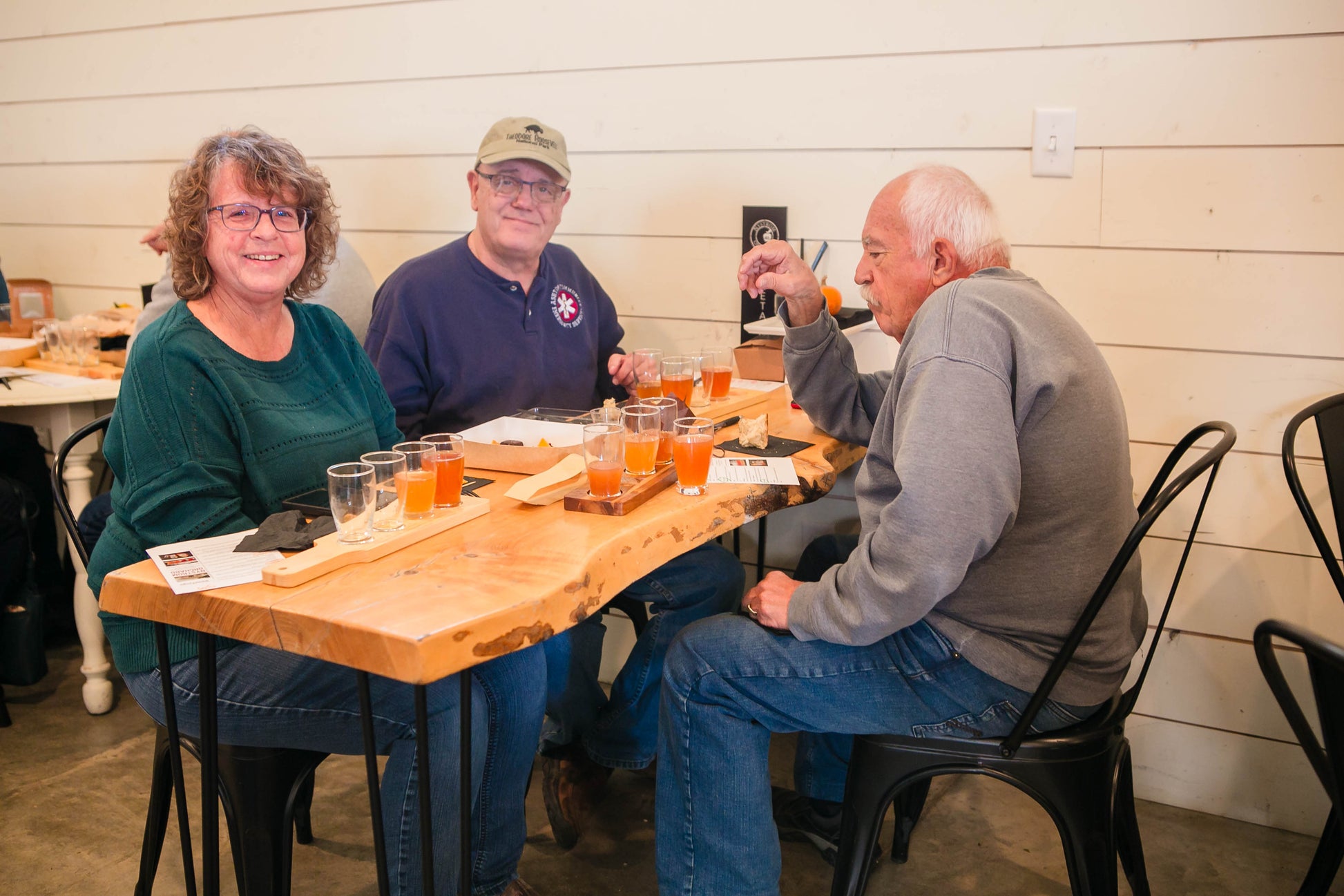 Three people sitting at a table with cold pressed apple cider. Hosted by Nystrom Orchard in Worthington Minnesota.
