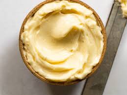 Whipped compound butter in a small bowl with a knife lying beside on a white table. Created in the kitchen of Nystrom Orchard in Worthington Minnesota. 