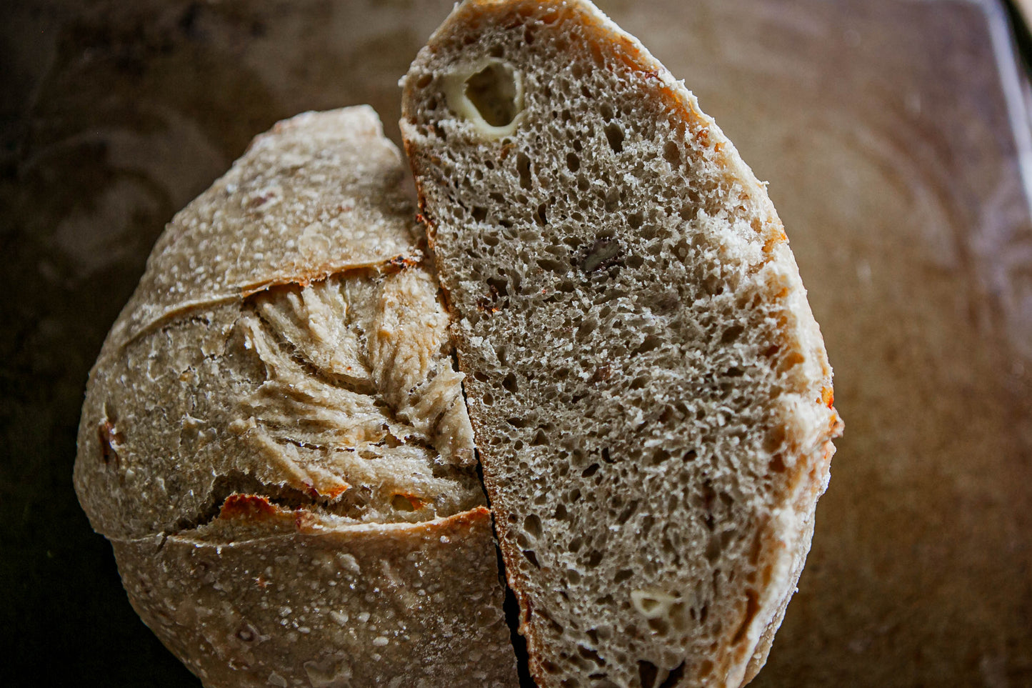 Close-up of a sliced loaf of honey gouda sourdough bread on a rustic wooden surface. Baked in the kitchen at Nystrom Orchard in Worthington Minnesota.