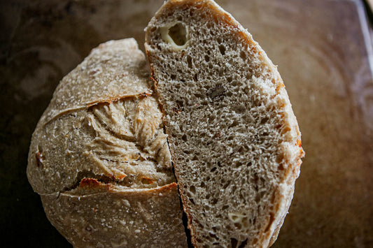 Close-up of a sliced loaf of honey gouda sourdough bread on a rustic wooden surface. Baked in the kitchen at Nystrom Orchard in Worthington Minnesota.