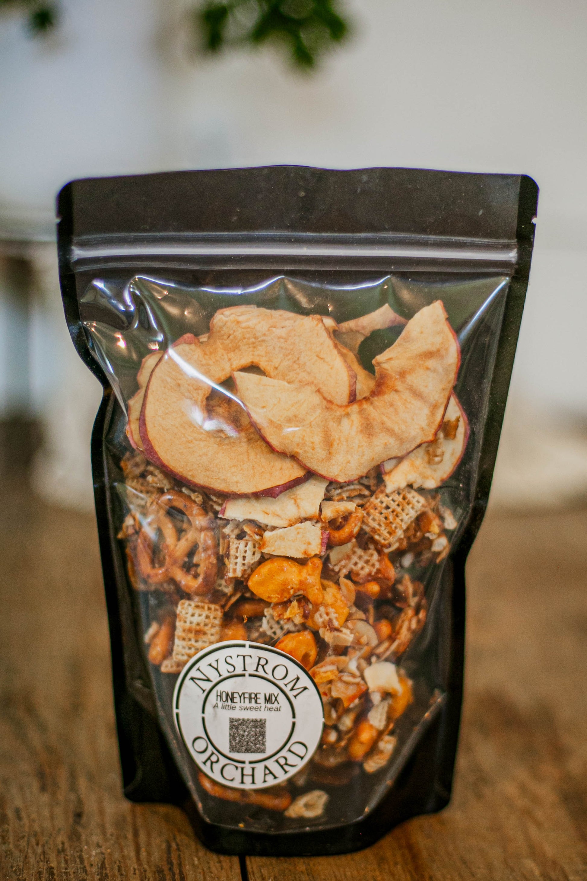 Packaged honeyfire snack mix with Nystrom Orchards branding on a wooden surface. Made in the kitchen of Nystrom Orchard in Worthington Minnesota.