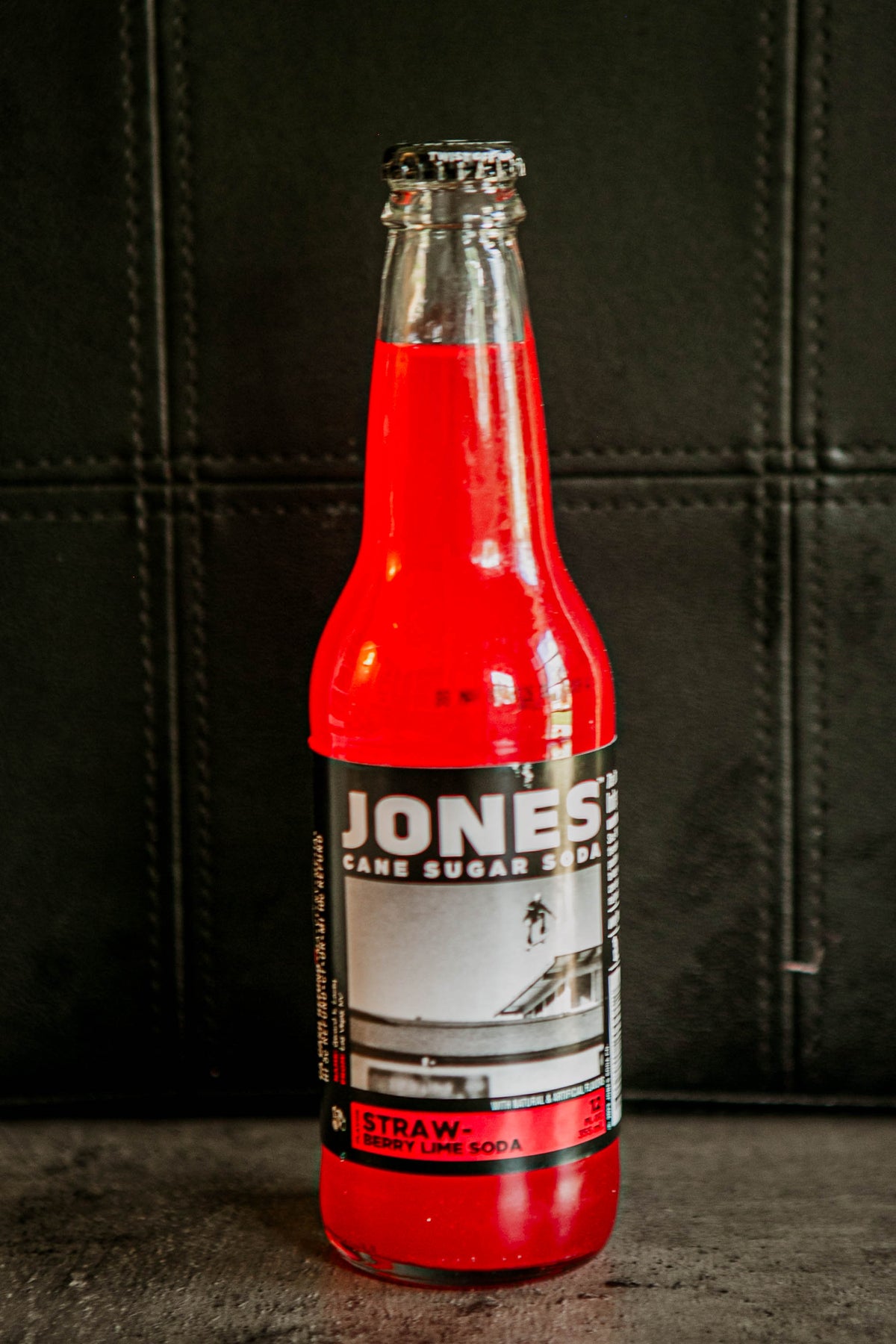Glass bottle of Jones strawberry lime flavored soda on a dark background. Sold in the store of Nystrom Orchard in Worthington Minnesota.