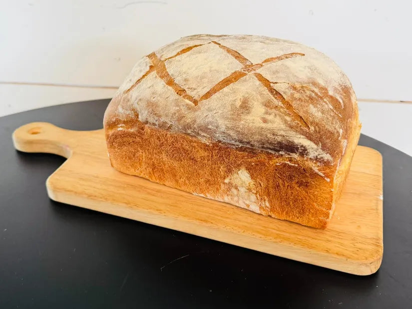 Loaf of sourdough sandwich bread on a wooden cutting board with a white background. Baked in the kitchen at Nystrom Orchard in Worthington Minnesota.