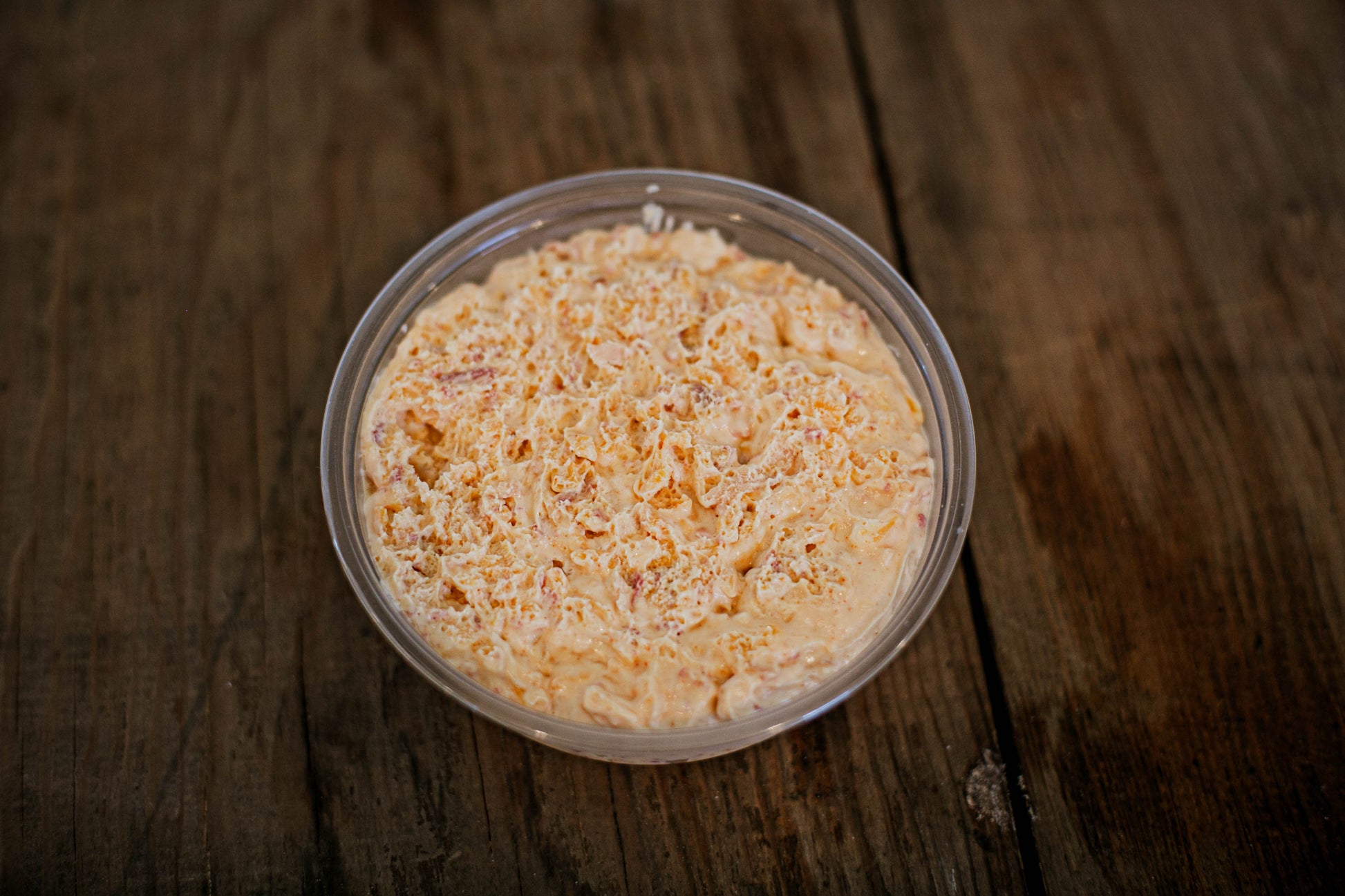 Container of maple bacon cheese dip on a wooden surface.  Made in the kitchen of Nystrom Orchard in Worthington Minnesota.