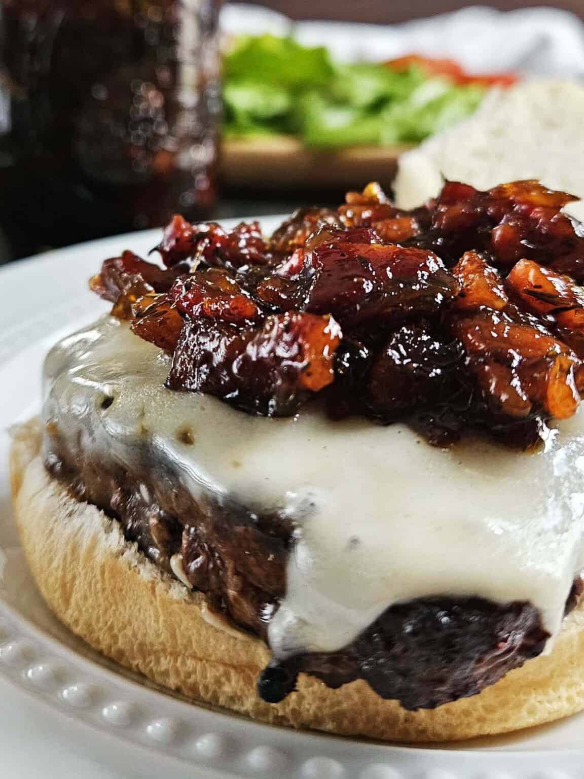 Close-up of a burger with cheese and maple bacon onion jam with a blurry background. Made in the kitchen of Nystrom Orchard in Worthington Minnesota.