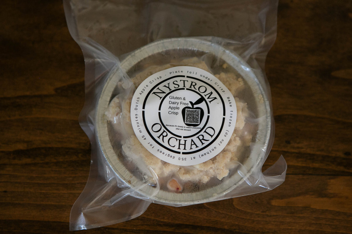A frozen vacuum sealed package of gluten dairy free apple crisp on a wooden surface. Made in Nystrom Orchard in Worthington Minnesota.