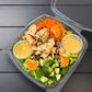 Salad with chicken, carrots, oranges, cucumbers, and citrus dressing in a small container in a clear container on a wooden surface. Made fresh in the kitchen at Nystrom Orchard in Worthington Minnesota.
