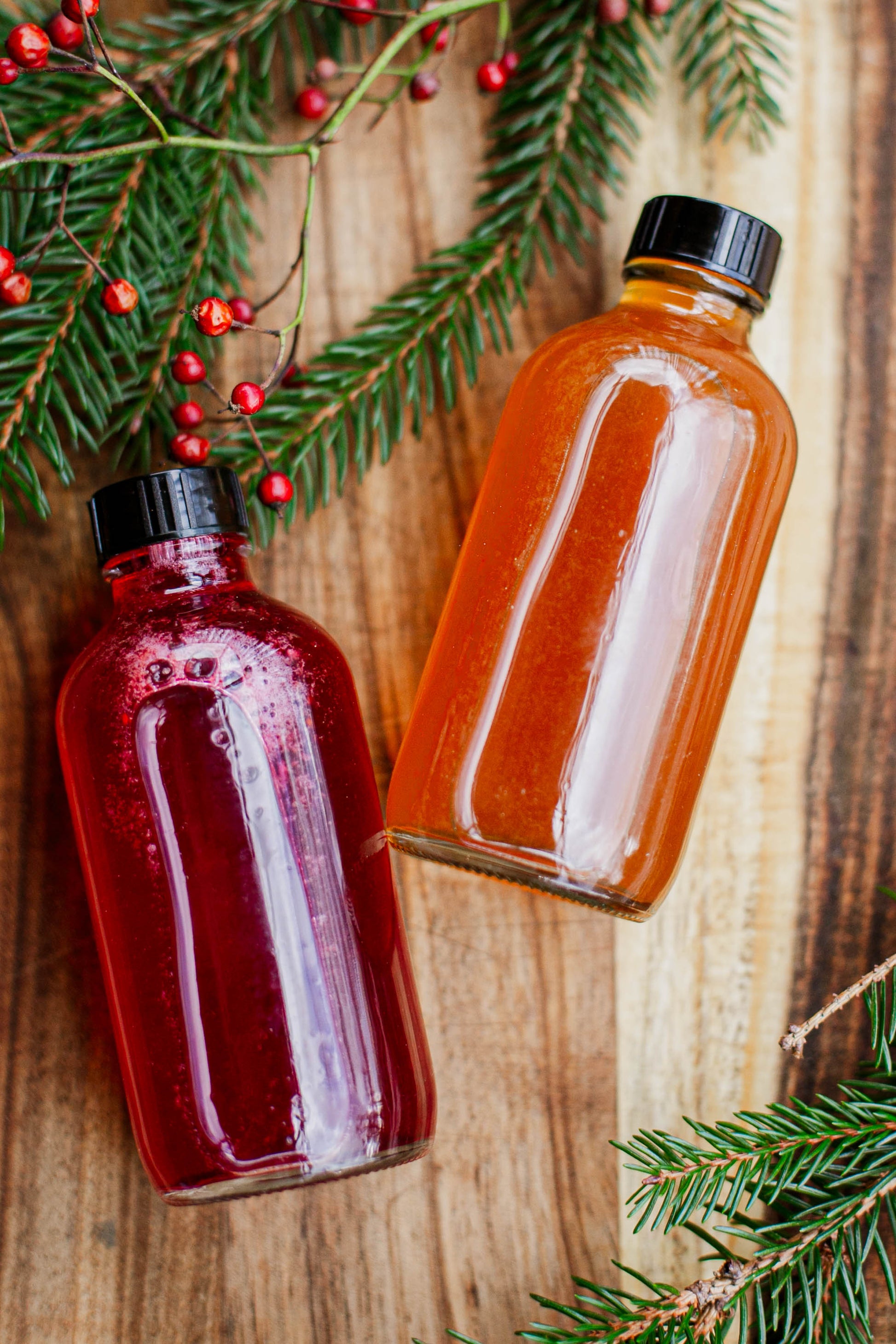 Two bottles of cider syrup on a wooden surface with Christmas decorations. Made in the kitchen at Nystrom Orchard in Worthington Minnesota.