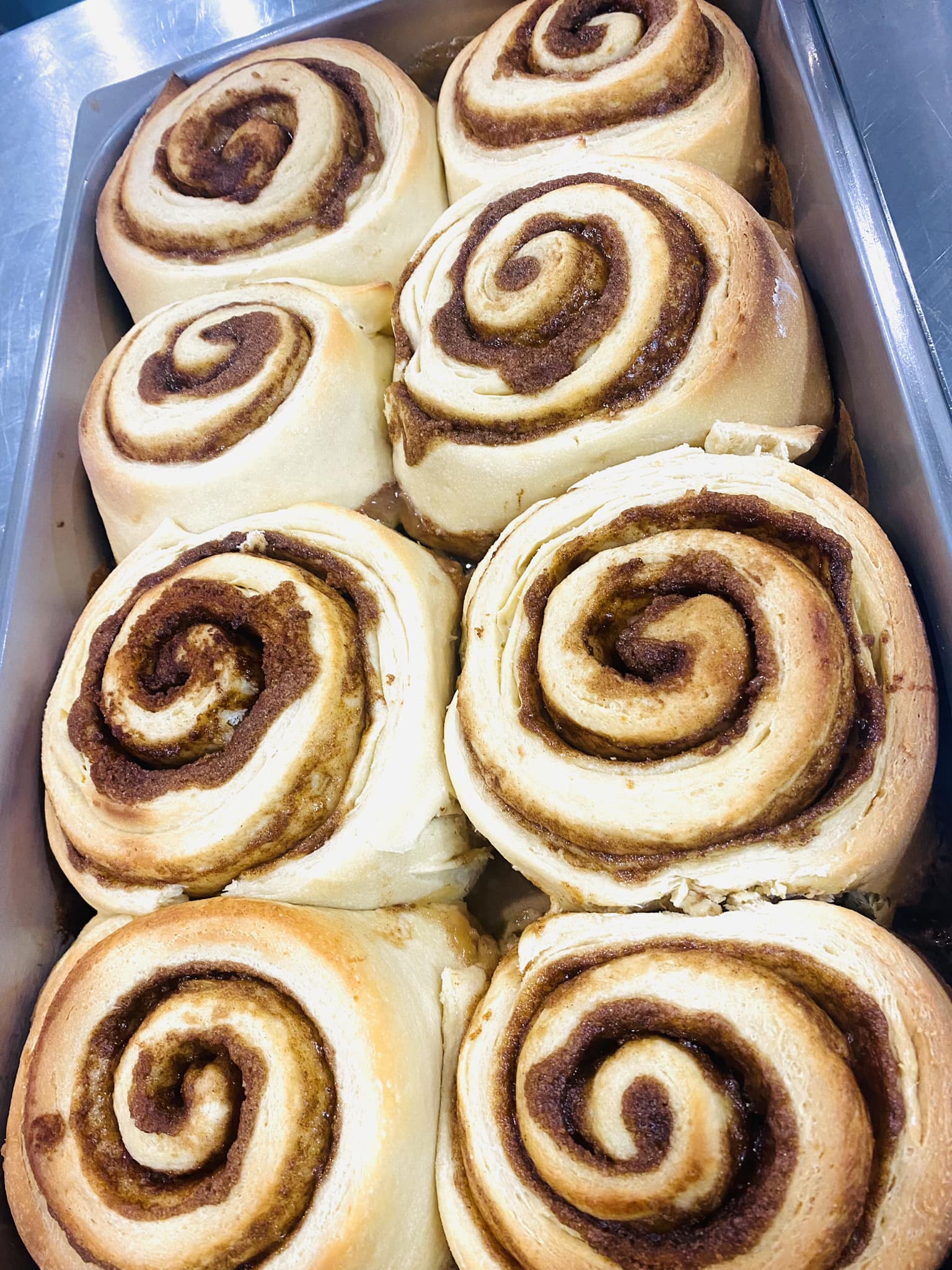 Pan of baked sourdough cinnamon rolls without frosting. on a metal table. Baked in the kitchen of Nystrom Orchard in Worthington Minnesota.