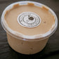 A plastic container of peanut butter cream cheese apple dip with a label that reads 'Nystrom Orchard' and has an image of an apple on a dark surface. Made in the kitchen of Nystrom Orchard in Worthington Minnesota. 
