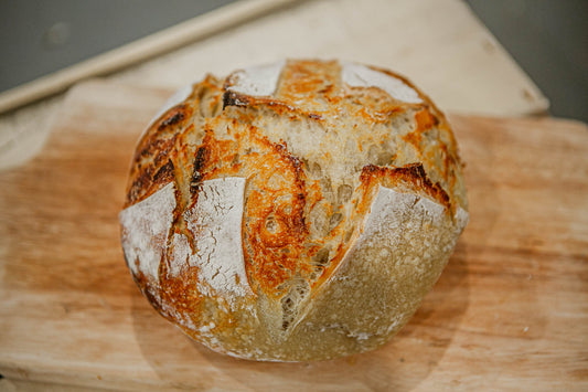 Loaf of Plain rustic sourdough bread on a wooden cutting board. Baked in the kitchen at Nystrom Orchard in Worthington Minnesota.