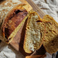 Loaf of rustic pumpkin sourdough bread sliced and buttered on a wooden cutting board on a white cloth. Baked in the kitchen of Nystrom Orchard in Worthington Minnesota.