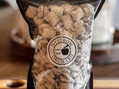 Bag of house made puppy chow a mixture of chex cereal chocolate, peanut butter and powdered sugar in a bag with a burry background. Mixed in the kitchen at Nystrom Orchard in Worthington Minnesota.