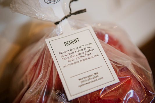 A pack of fresh Regent apples with a label attached, indicating the variety and the brand. Picked in Nystrom Orchard in Worthington Minnesota.