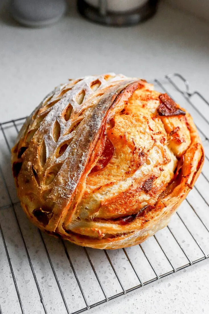 Artisan loaf of pizza sourdough bread on a cooling rack on a white countertop. Baked in the kitchen at Nystrom Orchard in Worthington Minnesota. 