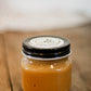 Jar of salted caramel on a wooden table with a white background. Made by the kitchen at Nystrom Orchard in Worthington Minnesota.