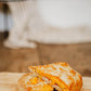 Soft pretzel wrap cut in half to show that its full of egg and cheese on a wooden cutting board with a blurry background. Baked in the kitchen of Nystrom Orchard in Worthington Minnesota.