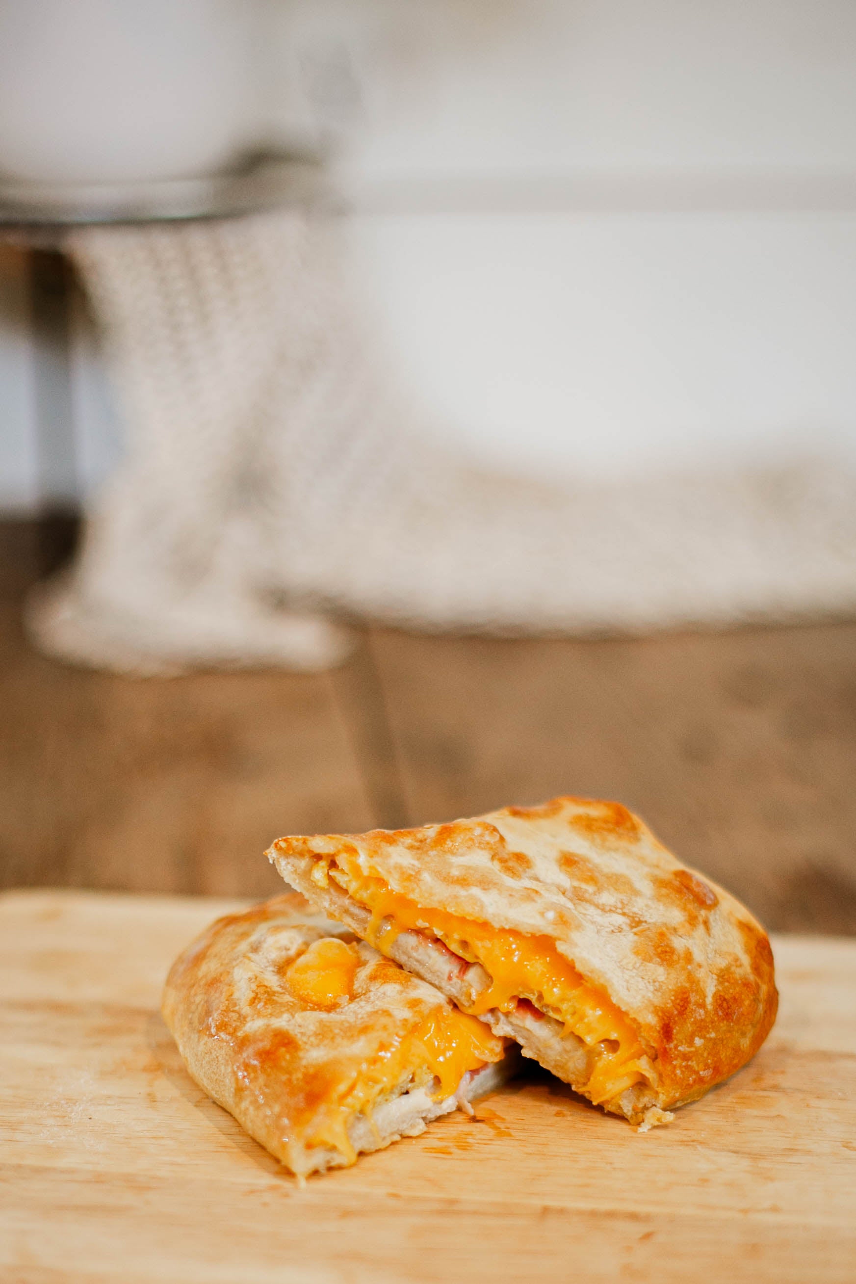 Soft pretzel wrap cut in half to show that its full of egg and cheese on a wooden cutting board with a blurry background. Baked in the kitchen of Nystrom Orchard in Worthington Minnesota.