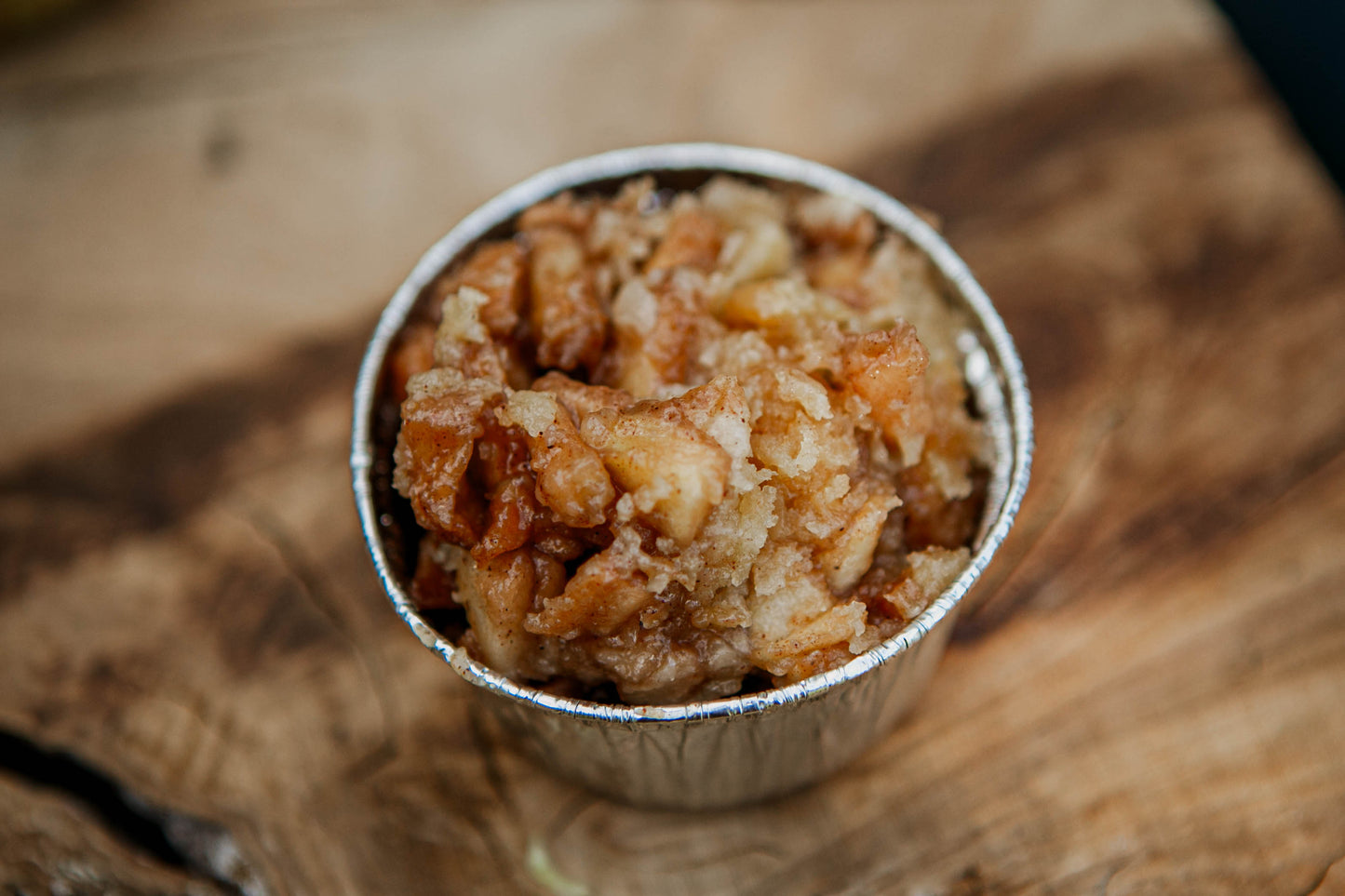 Scalloped apples in a single serving foil container on a wooden surface. Made in the kitchen of Nystrom Orchard in Worthington Minnesota.