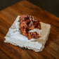 Frozen apple spice cheesecake with spiced apples and whipped cream on a wooden cutting board. Made in the kitchen of Nystrom Orchard in Worthington Minnesota. 