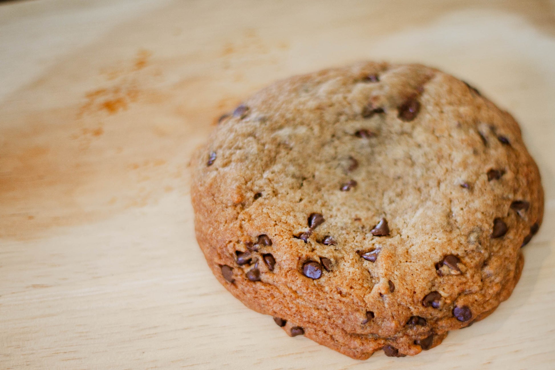 Sourdough browned butter chocolate chip cookie on a wooden surface.  Baked in the kitchen of Nystrom Orchard in Worthington Minnesota.