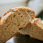 Close up of a rustic loaf of tomato basil sourdough bread cut in half on a dark surface with a blurry background. Baked in the kitchen of Nystrom Orchard in Worthington Minnesota.  