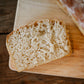 A slice of sourdough sandwich bread on a wooden cutting board with a blurred loaf in the background. Baked in the kitchen at Nystrom Orchard in Worthington Minnesota.
