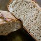 Close up of a loaf of roasted garlic cream cheese sourdough cut in half so you can see texture on a dark surface. Baked in the kitchen at Nystrom Orchard in Worthington Minnesota.