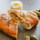 A soft pretzel wrap cut in half to show its full of smoked pulled pork surrounded by bbq, honey mustard and pickles on a dark surface. Baked in the kitchen of Nystrom Orchard in Worthington Minnesota.