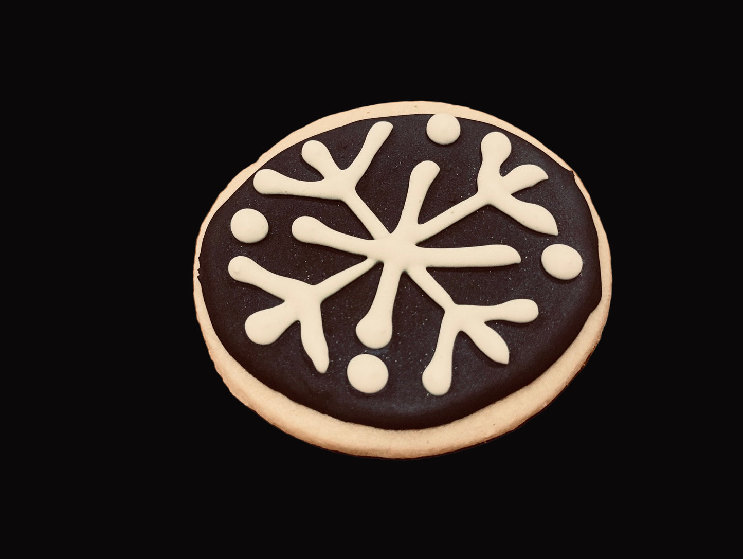 Sugar cookie with white snowflake design on a dark background. Baked by the kitchen at Nystrom Orchard in Worthington Minnesota.