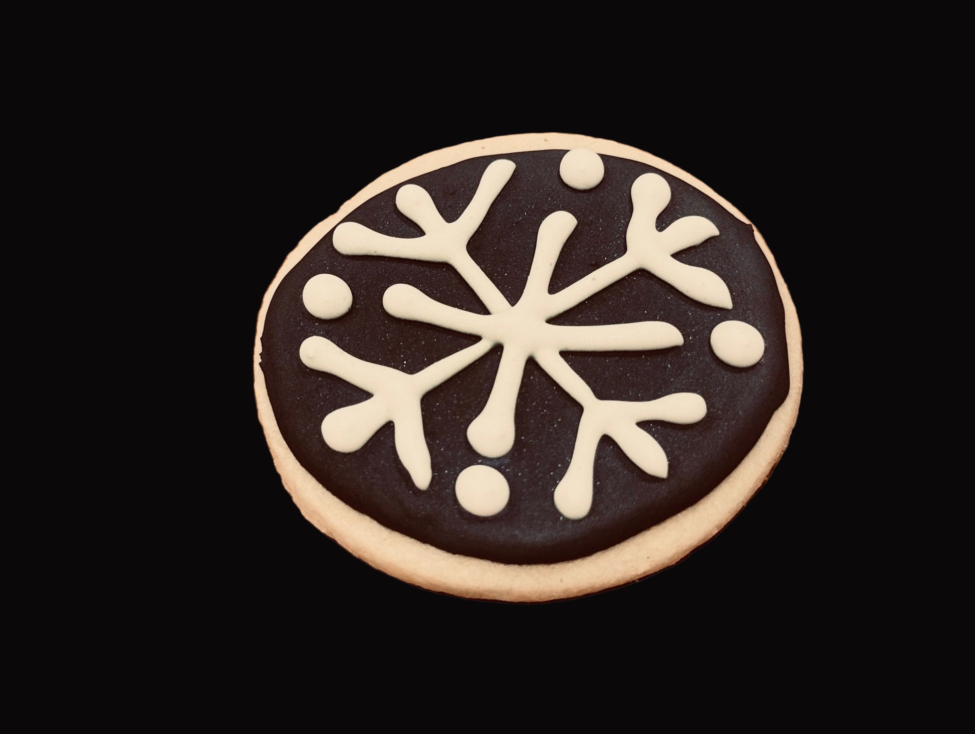 Sugar cookie with white snowflake design on a dark background. Baked by the kitchen at Nystrom Orchard in Worthington Minnesota.