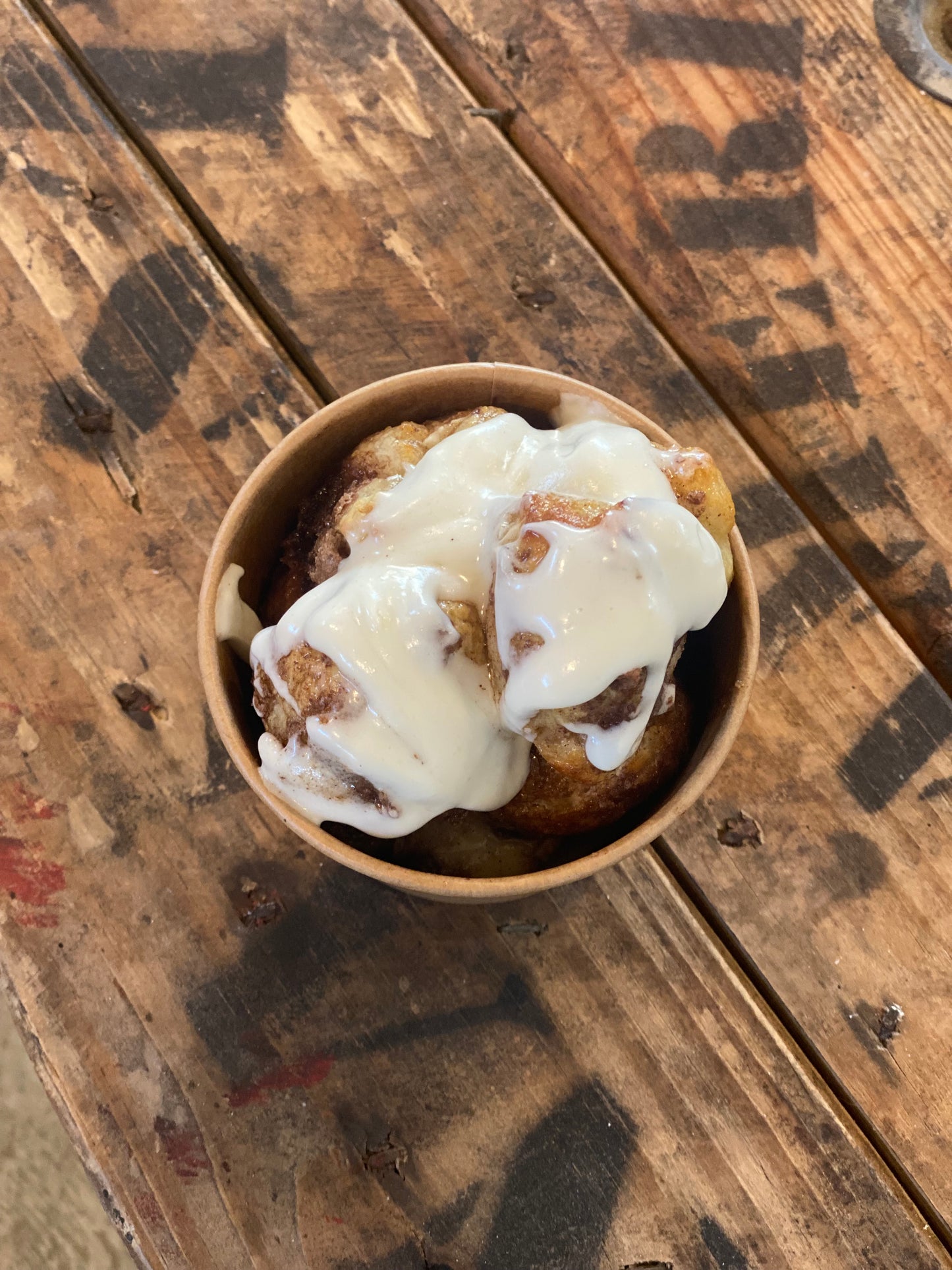 Cinnamon sugar soft pretzel bites with cream cheese frosting on top in a cup on a wooden surface. Baked in the kitchen of Nystrom Orchard in Worthington Minnesota.