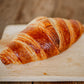 Homemade sourdough croissant on a wooden cutting board with a blurred wooden background. Baked in the kitchen of Nystrom Orchard in Worthington Minnesota.