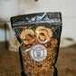 Bag of homemade sourdough granola with dried apples on a wooden surface, featuring the Nystrom Orchard brand. Made in the kitchen of Nystrom Orchard in Worthington Minnesota.