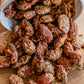 Spiced almonds on a wooden surface with a small white bowl. Made in the kitchen at Nystrom Orchard in Worthington Minnesota.