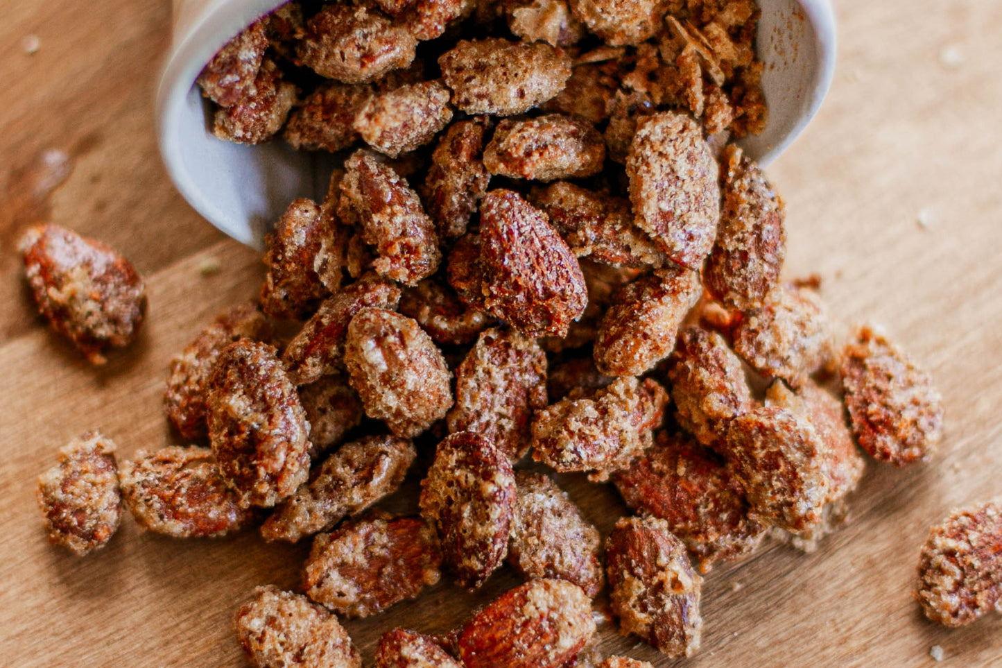 Spiced almonds on a wooden surface with a small white bowl. Made in the kitchen at Nystrom Orchard in Worthington Minnesota.