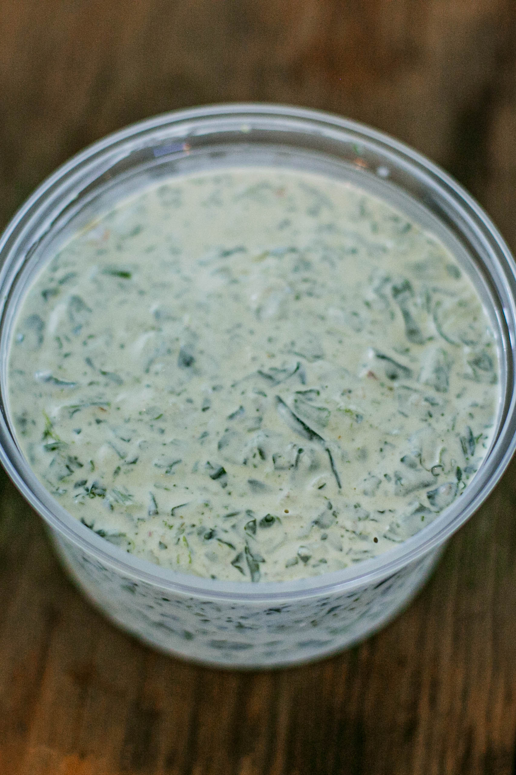 Container of creamy spinach dip on a wooden surface. Mixed in the kitchen of Nystrom Orchard in Worthington Minnesota.