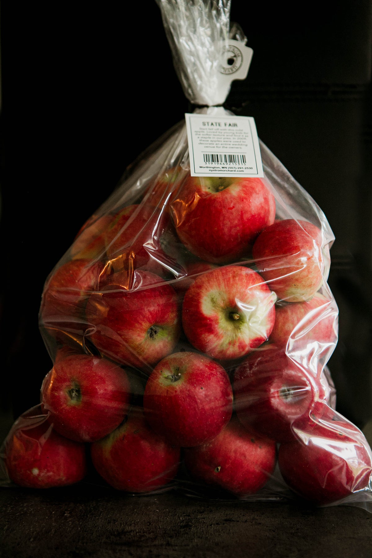 A clear plastic 5 lb bag filled with red State Fair apples, tied at the top with a white twist tie. Picked in Nystrom Orchard in Worthington Minnesota.