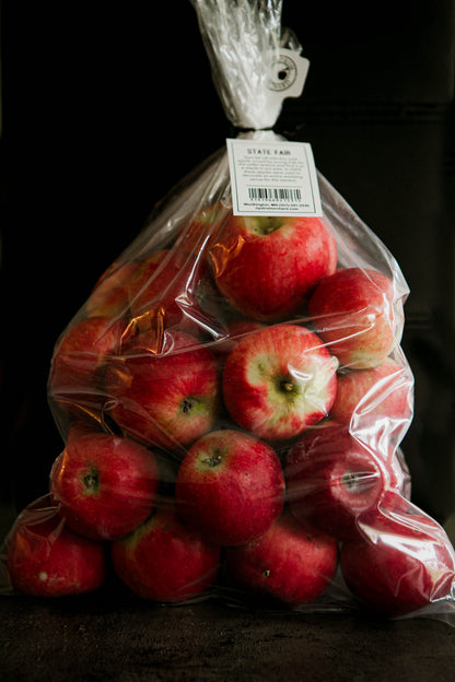 A clear plastic 5 lb bag filled with red State Fair apples, tied at the top with a white twist tie. Picked in Nystrom Orchard in Worthington Minnesota.