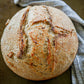 Rustic Loaf of tomato basil sourdough bread on a dark surface with a blue cloth. Baked in the kitchen at Nystrom Orchard in Worthington Minnesota.