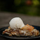 Warm dutch apple pie with a scoop of icecream on a black plate with a blurry background. Baked in the kitchen of Nystrom Orchard in Worthington Minnesota.