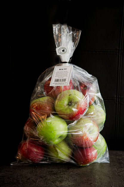 A plastic bag filled with red and green Wealthy Apples, with a label visible at the top. Picked in Nystrom Orchard in Worthington Minnesota.