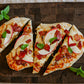 White cheddar bacon apple flatbread with a sprinkle of fresh basil on a wooden board on a white background. Baked in the kitchen at Nystrom Orchard in Worthington Minnesota.