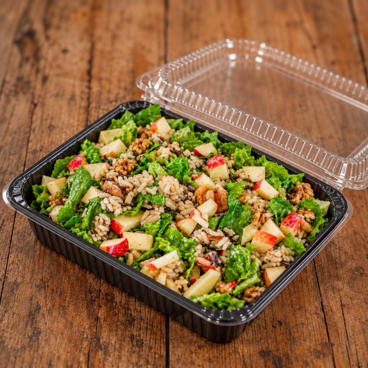 Black tray with apple wild rice salad on a wooden surface with a domed lid. Made in the kitchen of Nystrom Orchard in Worthington MN.