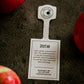 Zestar tag displayed on a textured surface with apples beside. Picked in Nystrom Orchard in Worthington Minnesota.