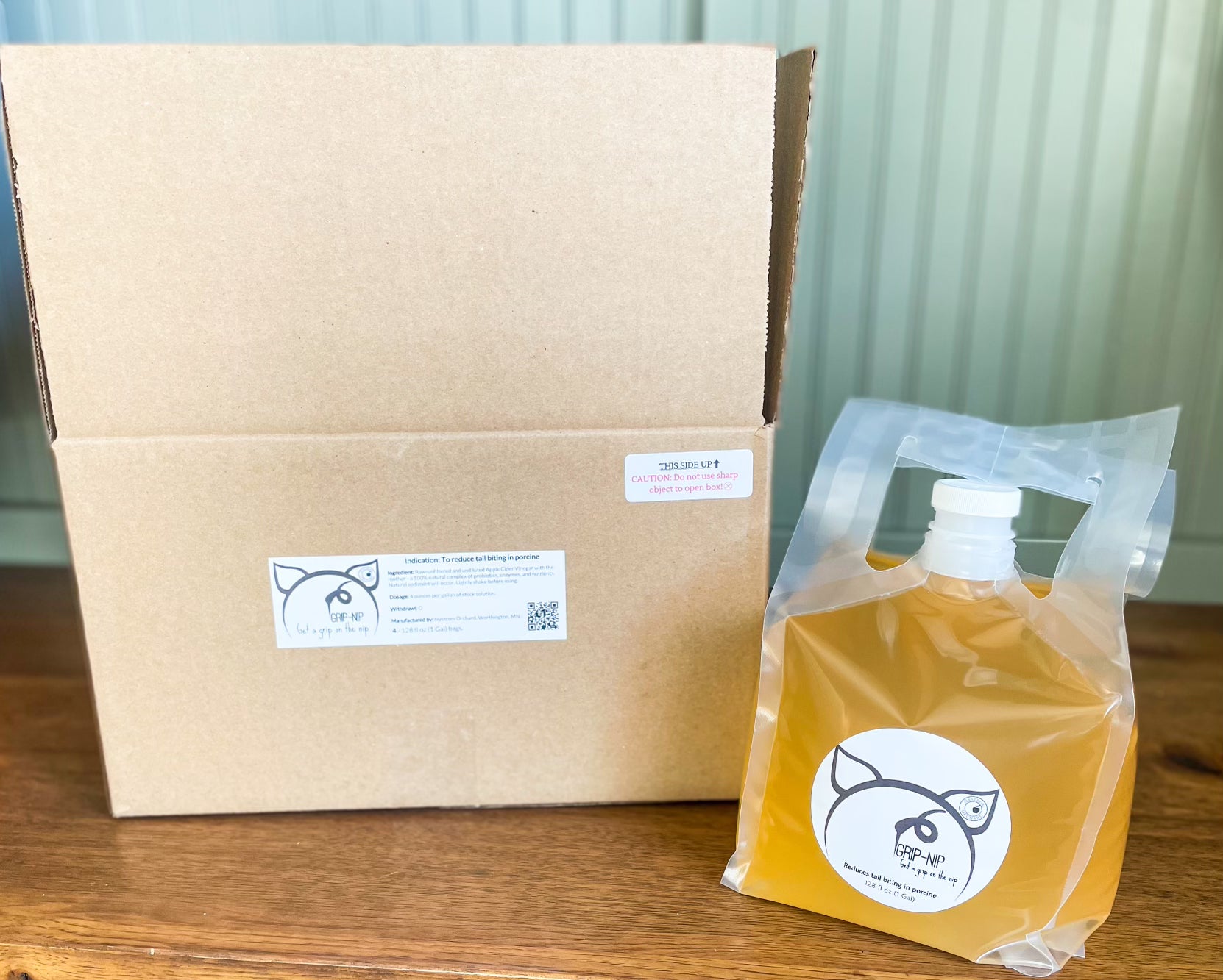 A cardboard box and a plastic bag with apple cider vinegar for animals. on a wooden surface. Made in the kitchen on Nystrom Orchard in Worthington Minnesota.