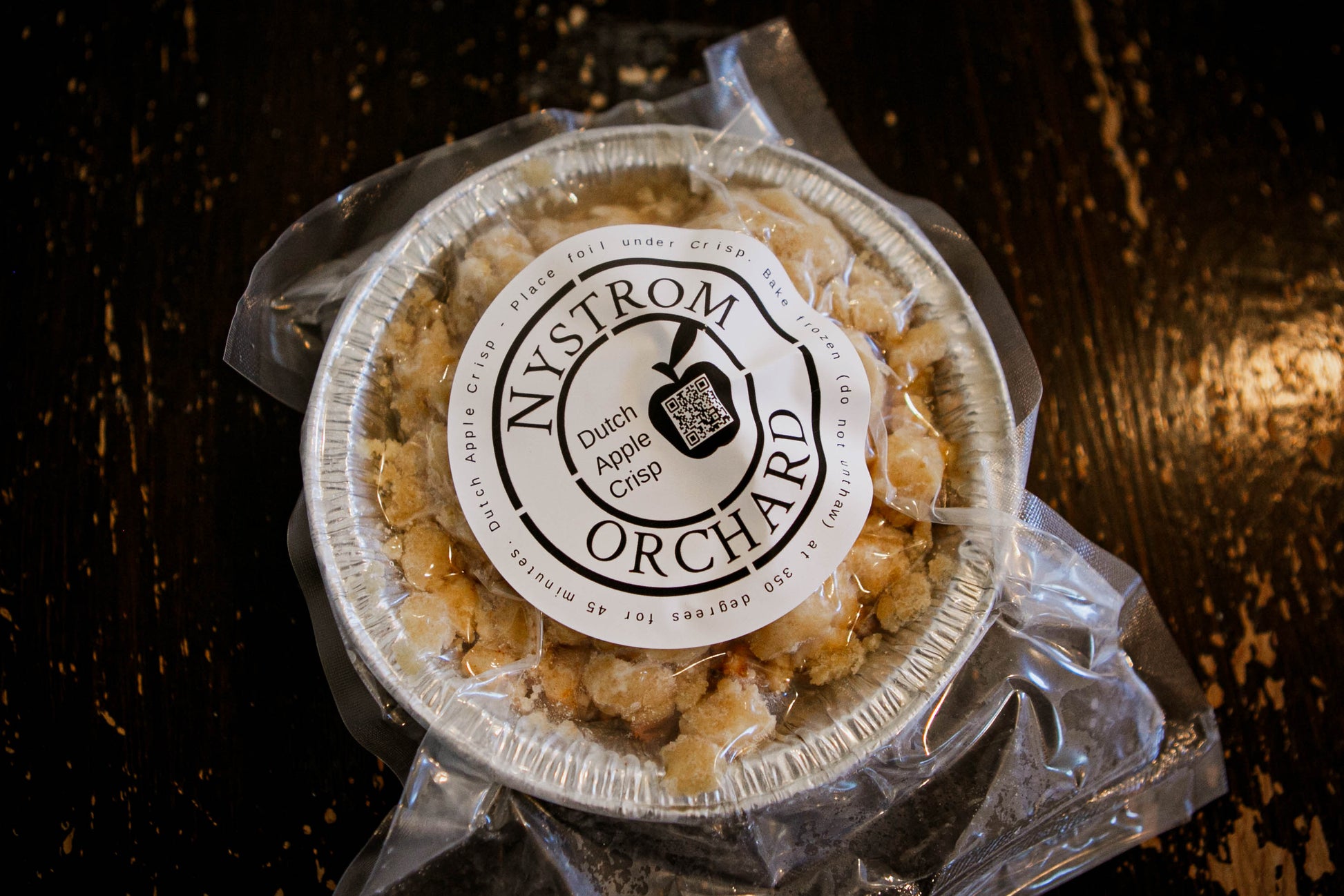 Frozen dutch apple crisp in a foil pan on  a dark surface. Made in the kitchen at Nystrom Orchard in Worthington Minnesota.