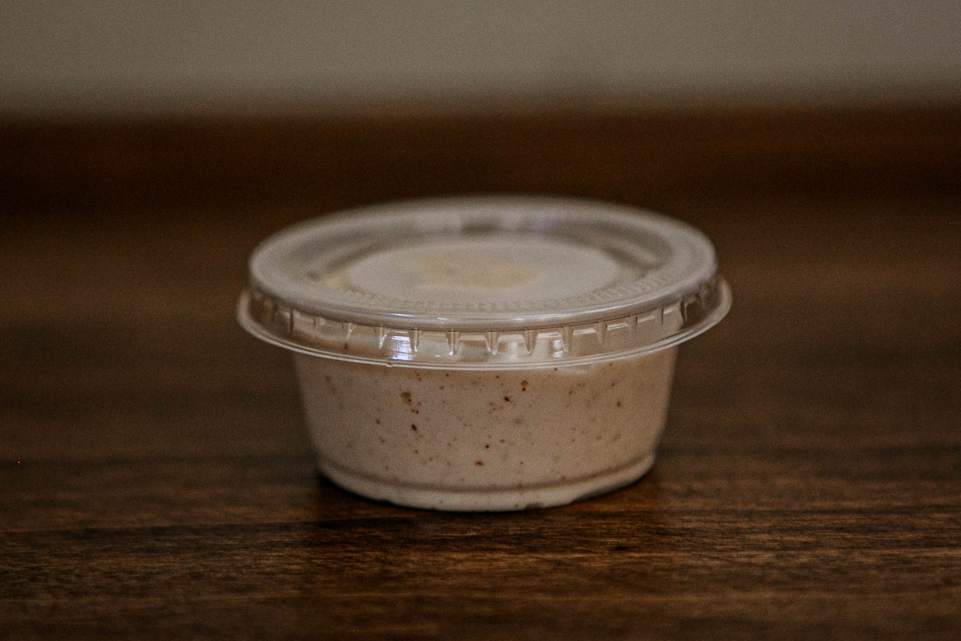 2 oz container with a lid full of apple pie dip on a wooden surface. Made in the kitchen of Nystrom Orchard in Worthington Minnesota.
